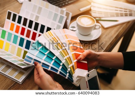 Hands of female designer in office working with colour samples. Woman at workplace choosing colourful paper charts. Close-up.