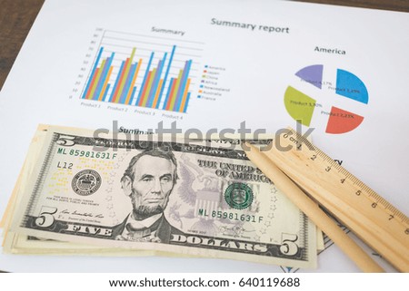 Business concept - American dollars banknote and graphs on wooden background