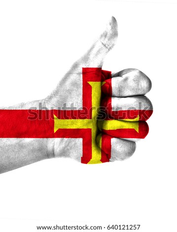Hand making thumbs up sign.Guernsey painted with flag as symbol of thumbs like,up,okay. Isolated on white background.
