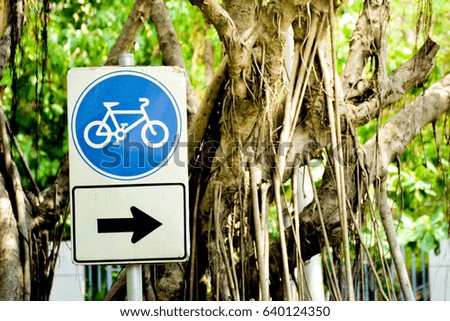 blue bicycle sign with arrow sign pole in the park