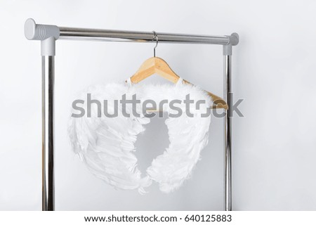 white angel wings on hanger for clothes open cloth rail wooden hanger on Grey Wall