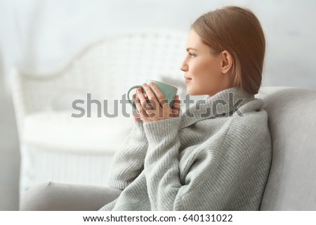 Beautiful young woman drinking tea while resting at home Royalty-Free Stock Photo #640131022