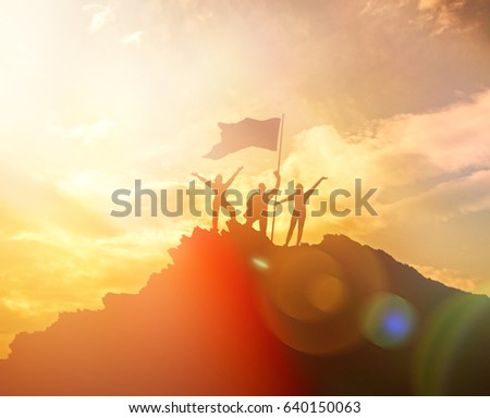 High performance, silhouettes of three people, raise the flag and hands up. A man on top of a mountain. Conceptual design. Against the dramatic sky with clouds at sunset. Success business. Royalty-Free Stock Photo #640150063