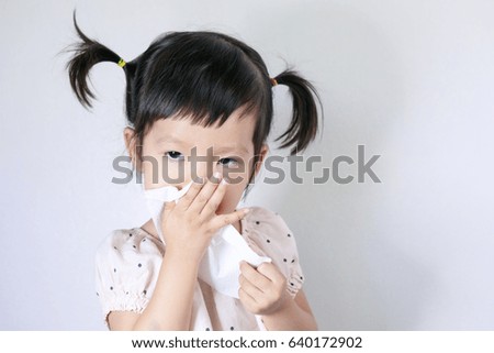 Asian Baby or A little cute asian girl blowing his nose with tissue paper in the white background