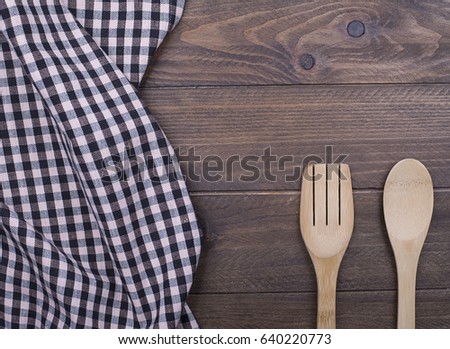 Background of plaid kitchen tablecloth and cutlery on wooden background. Copy space. Concept.