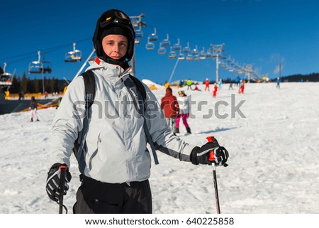 Male in ski-suit, helmet and ski goggles is skiing in a ski-resort in winter period