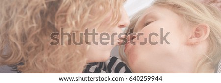 Mother giving kiss to her little daughter, panorama