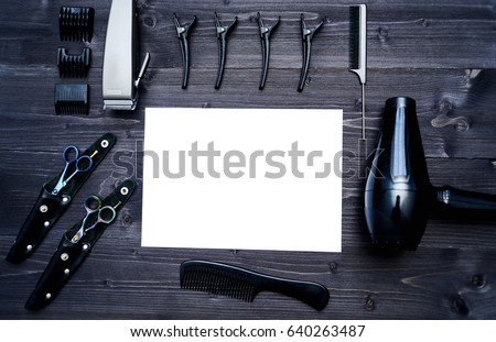 Hairdresser tools on wooden background. Blank card with barber tools flat lay. Top view on wooden table with scissors, comb, clipper and hairdryer with empty white paper, free space