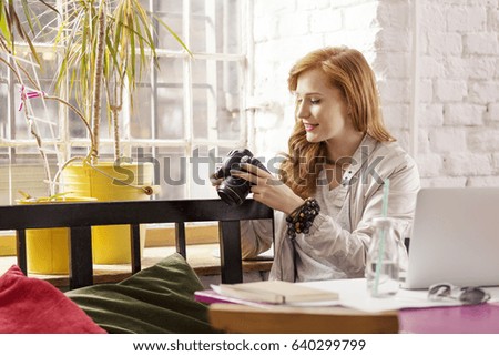 Redhead female freelance photographer drinking water in industrial interior