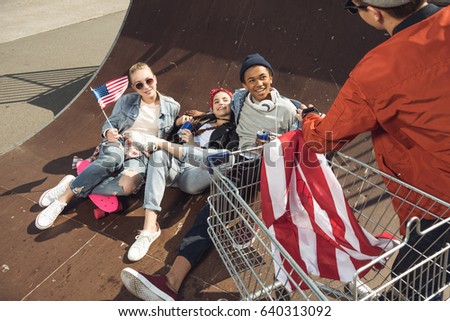 teenagers having fun and lying with american flag in skateboard park, hipster style concept 