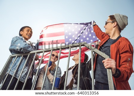 teenagers having fun and waving american flag in skateboard park, hipster style concept