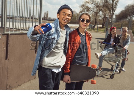 teenagers having fun with shopping cart in skateboard park, hipster style concept