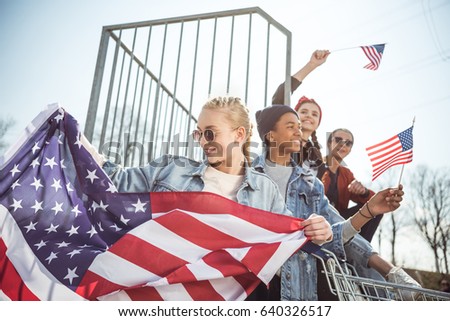 Happy teenagers group having fun and waving american flags at sunset