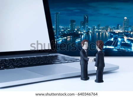 Miniature figures businessman shaking hands, laptop and city scape in background, can put emotion on blank face