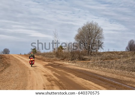 A young male cyclist rides a bicycle on a dirt road. Around the forest, trees. Spring.