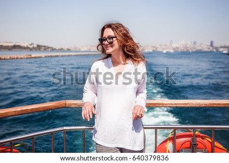 Woman with curly hair on the sea terrace.pretty cuter teenager,gossip.emotions,girl wearing stylish outfit,girl in sunglasses,white shirt.Bright spring colors,grey pants,casual,happy,yacht,laugh