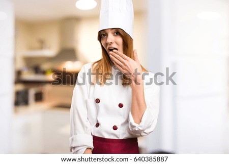 Beautiful chef woman making surprise gesture in the kitchen