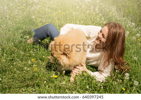 Young smiling girl having fun with her dog outdoor.