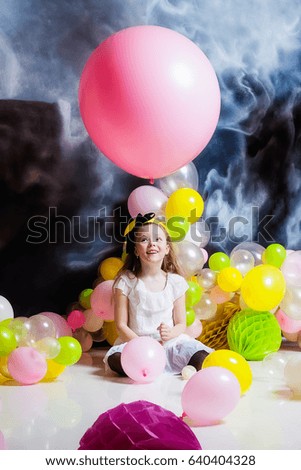 Girl is sitting on the floor surrounded by balloons