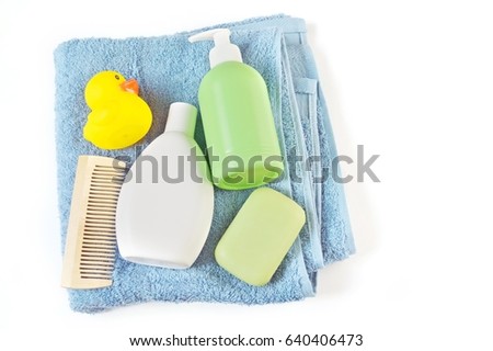 Shampoo, balm for hair, a wooden comb, soap, a blue terry towel and a yellow rubber duck. Bathroom Set. Flat lay photography. Organic cosmetics for hair care