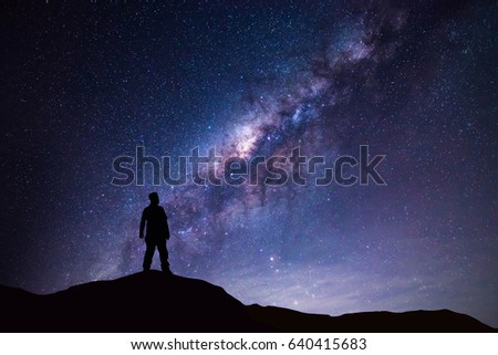 Milky Way landscape. Silhouette of Happy man standing on top of mountain with night sky and bright star on background.  Royalty-Free Stock Photo #640415683