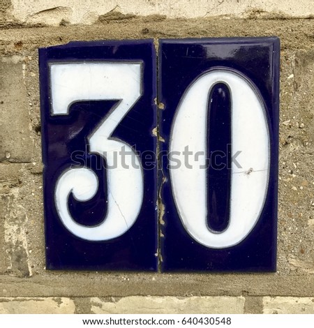 Number 30 thirty three zero blue tile house number address sign brick wall textured background