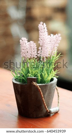 plastic pink flowers in the wooden pot on the wooden table, soft focus, selective focus