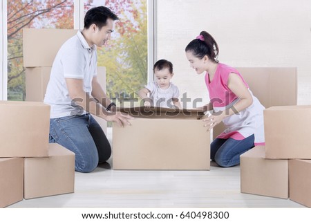 Picture of a little child with her parents unpacking boxes together in the new house