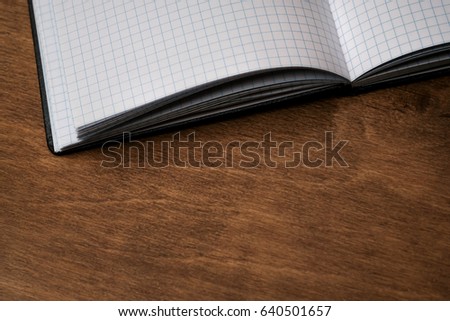 Open the notebook in a cage on a wooden table. Open the laptop on your desktop. Open notebook, diary in the box. Close-up photo. Business concept, place for text. Copy space for your text