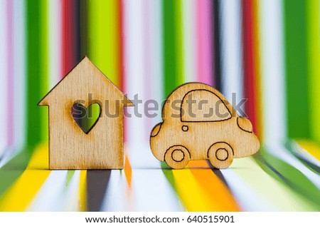 Wooden house with hole in form of heart with wooden car icon on colorful striped background. Concept of moving. Symbol of traveling.