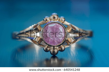 Gold ring with pink gemstone on a blue background