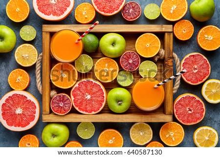 Citrus fruits sliced harvest mix flat lay in wooden tray on blue concrete background, healthy vegetarian organic food, antioxidant detox diet. Tropical summer mix grapefruit, orange, apple, kiwi fruit