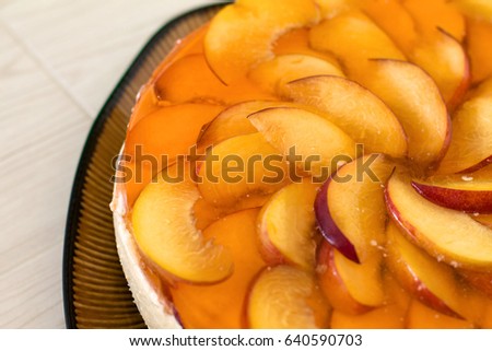 Fruit cake with peach, jelly and mousse in plate on wooden background.