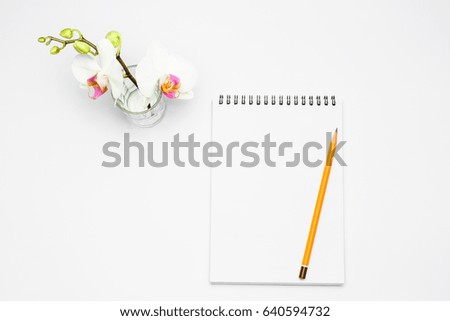 Open notebook with pencil and Flowers orchid, office decoration concept.