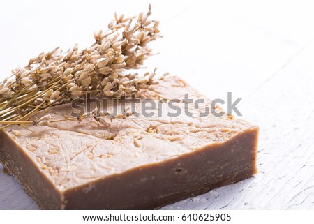 organic soap with a bunch of dried lavender flowers on white wood background
