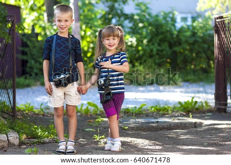 Little boy and a little girl with two vintage cameras standing together holding hands. Amazing children