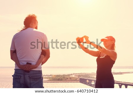 Woman photographs the loving couple at sunset