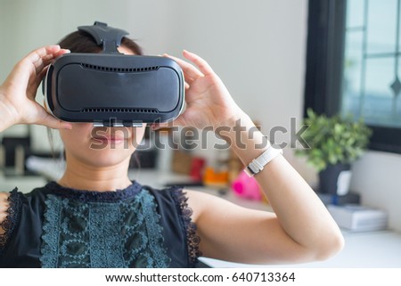 Asian people using VR for watch and play game at home.