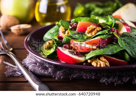 Healthy salad plate with apple, dried cranberry, walnut, spinach and poppy seed dressing on wooden background close up. Food and health. Clean eating.