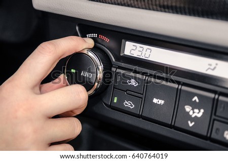 Hand adjusting the internal temperature of the car by turning the temperature control knob. Royalty-Free Stock Photo #640764019