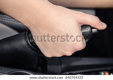 Hand pulling the car handbrake.