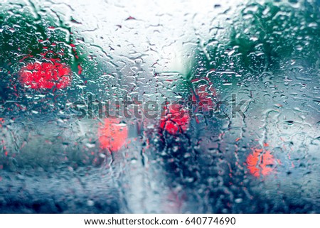 Traffic in rainy day with drops of rain. Street bokeh lights out of focus. 