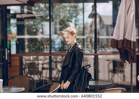 young model with blonde hair on city streets using cell phones