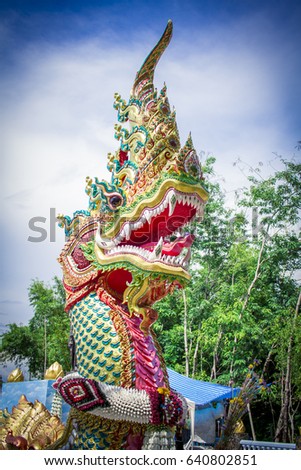 Head of naga statue image in Thai temple with blue sky background.