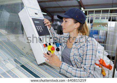 beautiful worker operating a machine in a factory