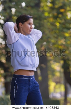 Young woman doing warming-up movements in a park.