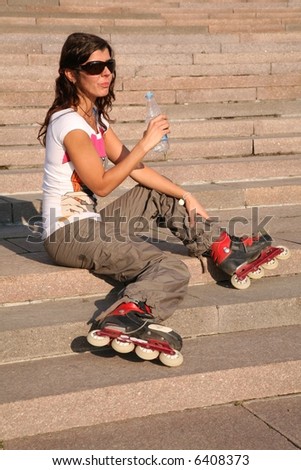 girl-roller sits on the stairs with the bottle of the water