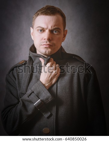 Young man in coat on dark background. Color toned.