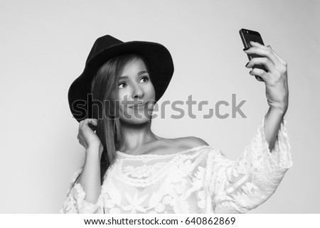 Attractive young woman looking at the phone, studio shot, black and white photo 