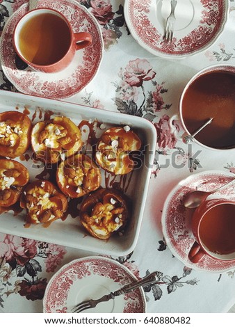 Baked apples with cream, salty caramel and almonds. Served with a vintage tea set